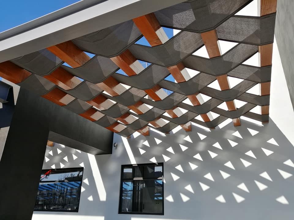 Detalle de pérgola metálica con patrón de sombra sobre fachada